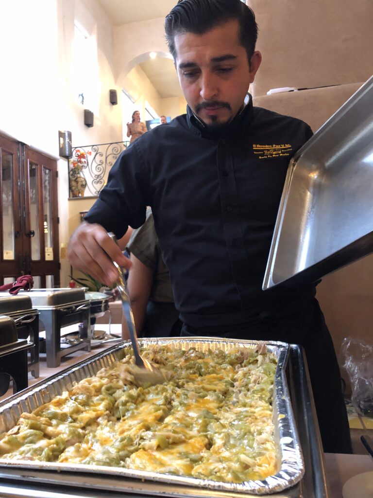 Server previewing green chile chicken enchiladas before an event starts. 